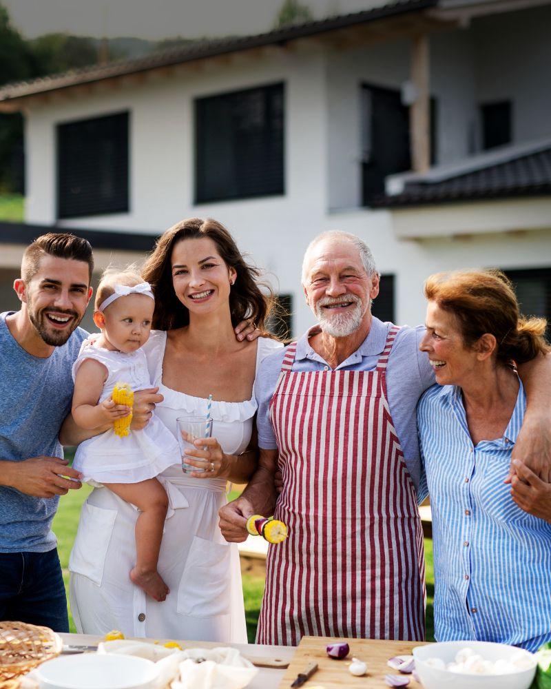 Three generations of a family, including grandparents, parents, and a young child, spending time together in their backyard